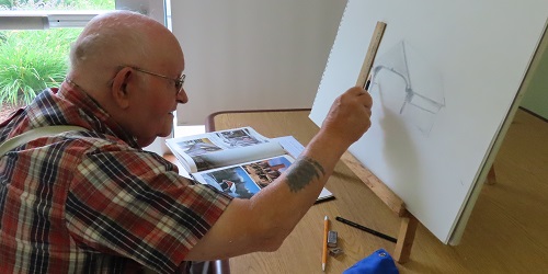 stanley a veterans draws on an easel while seated