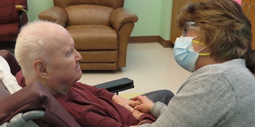 New Hampshire Veterans Home nurse holding a smiling veteran's hand
