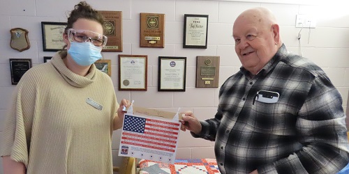 Veterans Home staff person presents a World War II banner to a veteran